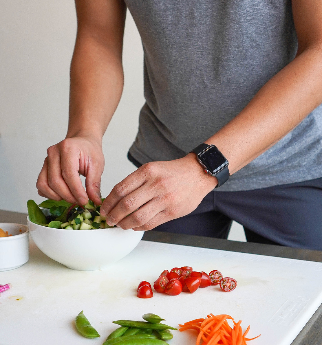 A man prepares a salad in a white bowl; healthy vegan food